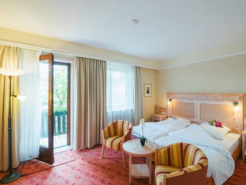Doppelzimmer mit Doppelbett, Sesseln, Tisch und Balkon