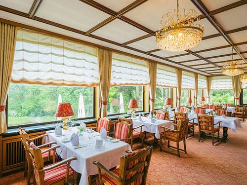 Restaurant mit weiß eingedeckten Tischen und bunten Stuhlpolster