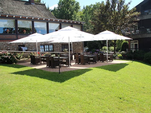 Hotel Terrasse bei Sonnenschein mit Rattan Möbeln und großen Sonnenschirmen