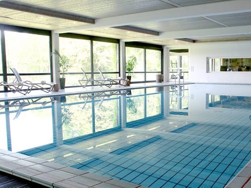 Indoor Pool im Wellnessbereich mit Relaxliegen am Rande