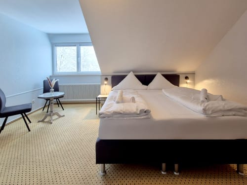 Zweibettzimmer mit Boxspringbett, zwei Stühlen und einem Tisch