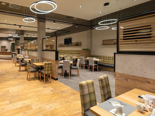 Lichtdurchfluteter Speisesaal mit modernem Interieur, Holzakzenten und eleganten Ringlampen