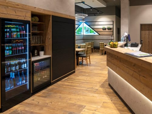 Beleuchteter Getränkekühlschrank und Blick in den Restaurantbereich