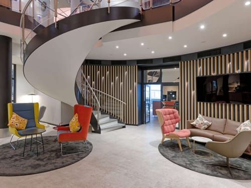 Modernes Büro-Lounge-Design mit geschwungener Treppe und stilvollen Sitzgelegenheiten