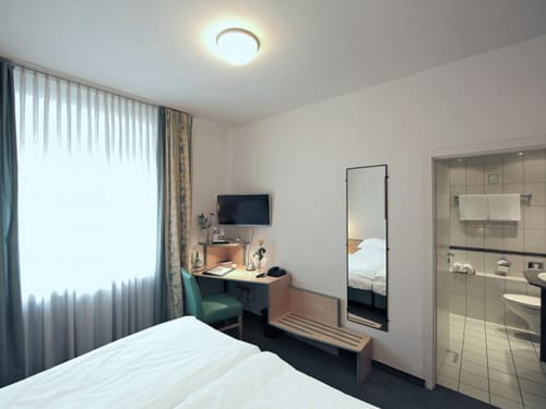 Doppelzimmerm mit Wandspiegel kleinem Schreibttisch und Zugang zum Bad