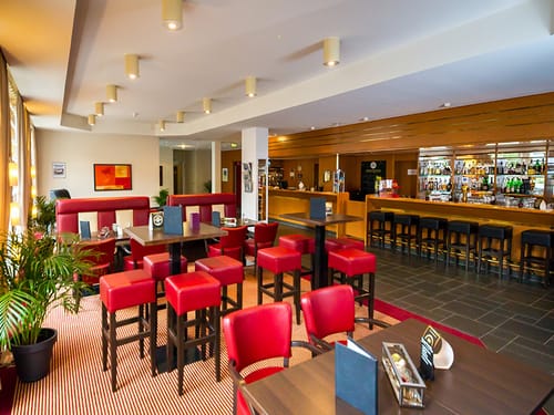Bar mit roten Barhockern und einer langen Theke