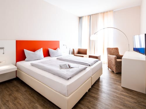 Doppelzimmer French mit Boxspringbett Sesseln, Tisch und TV