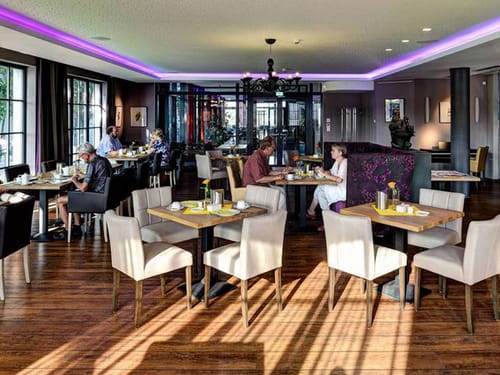 Hotel Restaurant mit verschiedenen gedeckten Tischgruppen