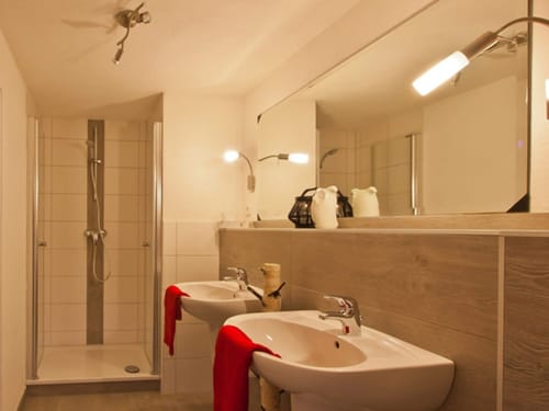Badbereich mit Dusche, zwei Waschbecken und großem Wandspiegel