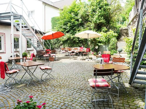 Innenhof mit verschieden Tischgruppen und Sonnenschirme