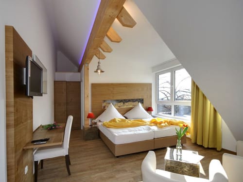 modern eingerichtetes Doppelzimmer mit TV, Doppelbett, Sessel, Tisch und Schreibtisch