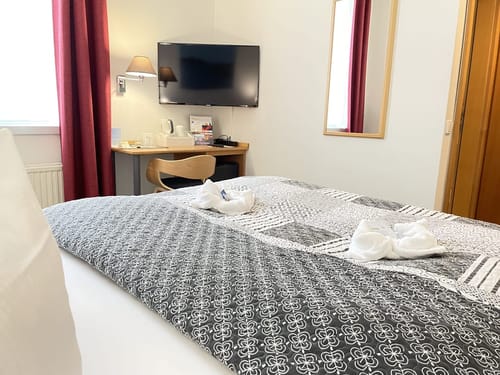 Blick auf das Boxspringbett, Schreibtisch, Stuhl und TV
