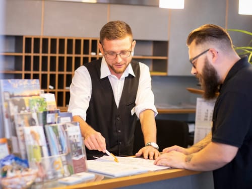 Mitarbeiter und Gast an der Hotelrezeption
