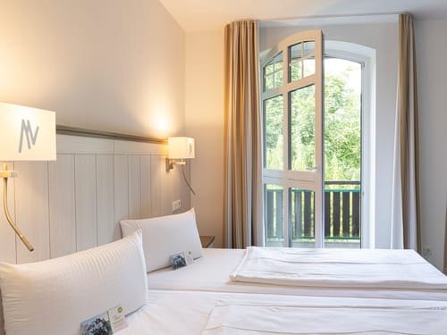 einfaches Zimmer mit Balkon, Leselampen und Nachttischen