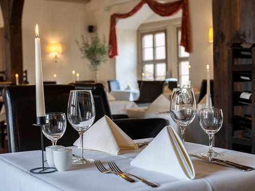 Gedeckter Tisch mit weißer Tischwäsche, Wein und Wassergläsern