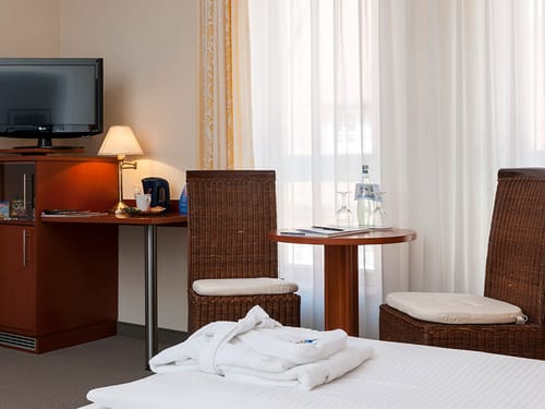 Sitzbereich im Doppelzimmer mit zwei Stühlen, Tisch, TV und Minibar