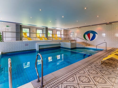 Modernes Hallenbad mit blauen Fliesen und gelben Liegestühlen