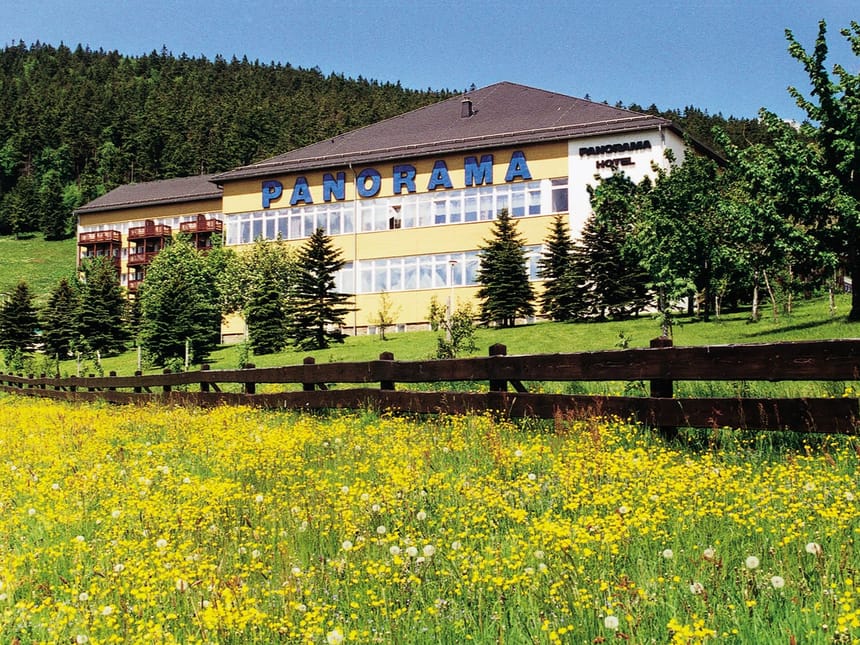 Idyllisches Panorama-Hotel vor einer Bergkulisse im Gruenen