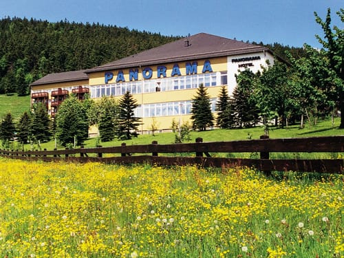 Idyllisches Panorama-Hotel vor einer Bergkulisse im Gruenen