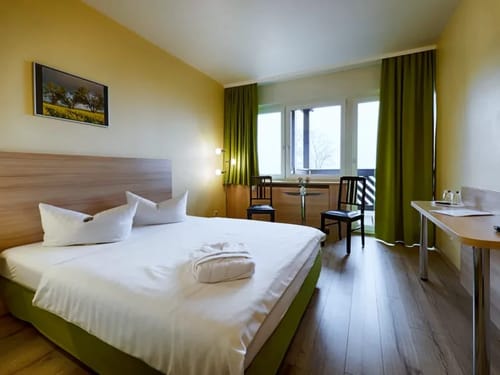 Modernes Hotelzimmer mit Doppelbett und großem Fenster