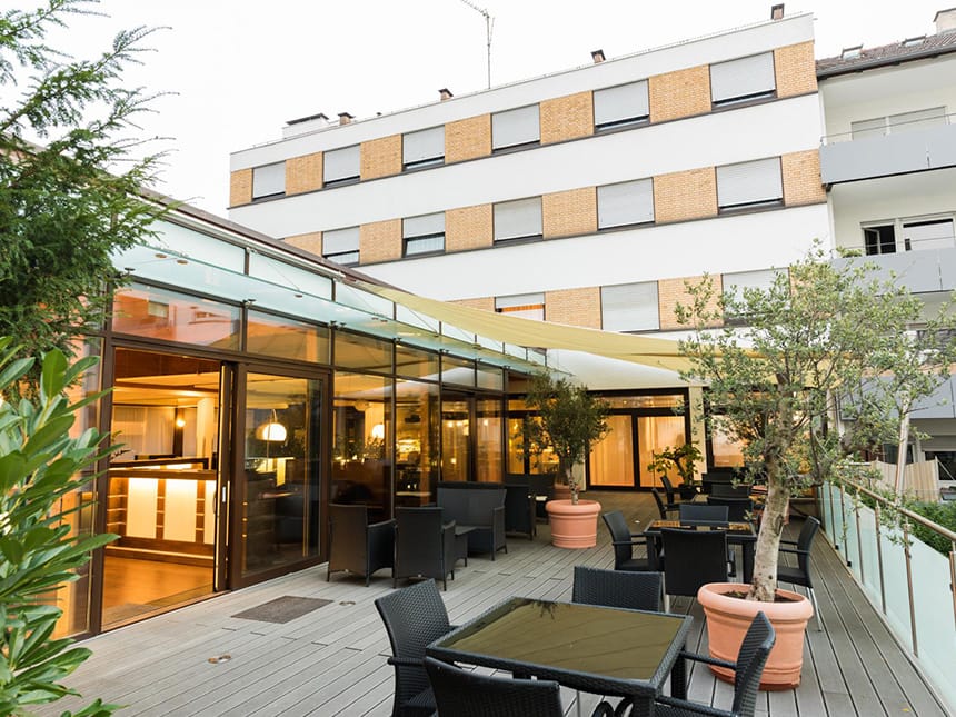 Hotelterrasse mit verschiedenen Tischgruppen und Zugang zum Hotel