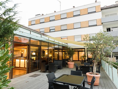 Hotelterrasse mit verschiedenen Tischgruppen und Zugang zum Hotel