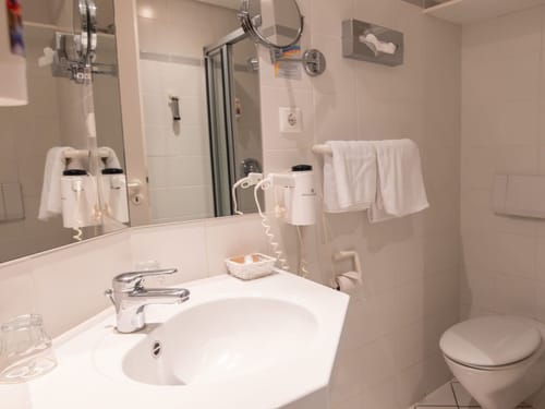 Modernes Badezimmer mit Waschbecken, Spiegel, und Duschbereich