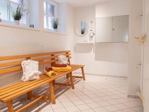 Moderner Umkleideraum mit Holzbank und Handtuechern.