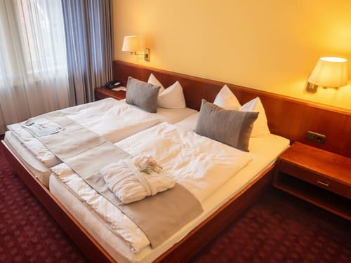 Gemütliches Hotelzimmer mit Doppelbett, Nachttisch und Lampen