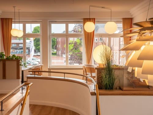Modernes Interieur eines Cafés mit großen Fenstern und stilvoller Beleuchtung.