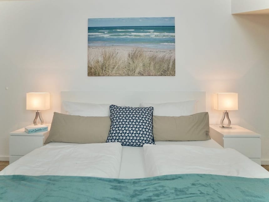 Großes Bett, Nachttisch, Lampen und ein Bild an der Wand