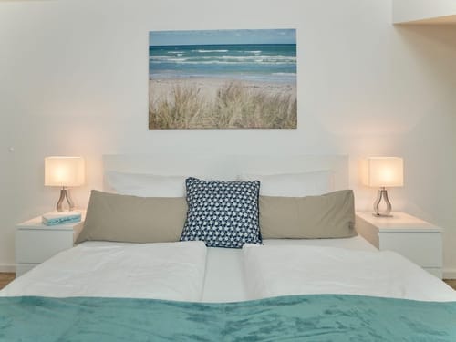 Großes Bett, Nachttisch, Lampen und ein Bild an der Wand