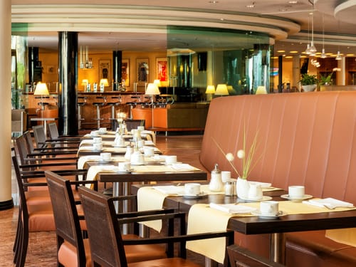 Frühstücksraum mit gedeckten Tische und einer Bar im Hintergrund