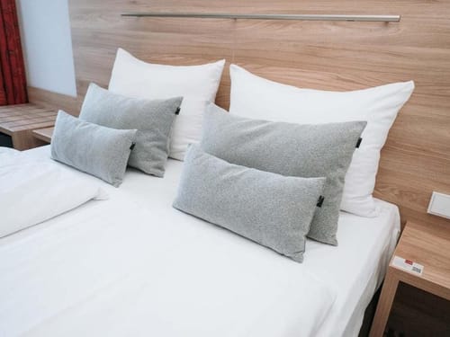 Modernes Schlafzimmer mit gemütlichem Doppelbett und mehreren Kissen auf Holz-Bettgestell.