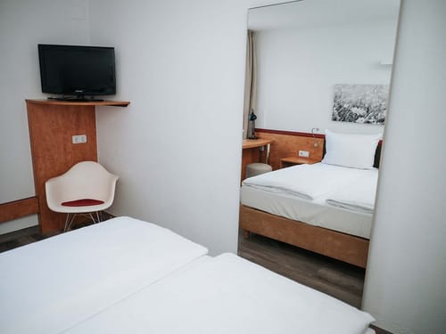Modernes Hotelzimmer mit Doppelbett, Fernseher und Stuhl