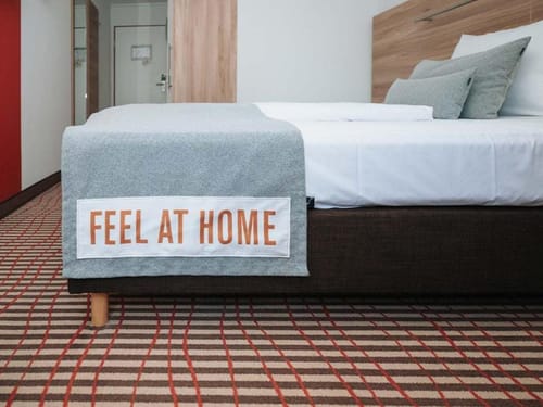 Gemütliches Hotelbett mit der Aufschrift "Feel at Home"
