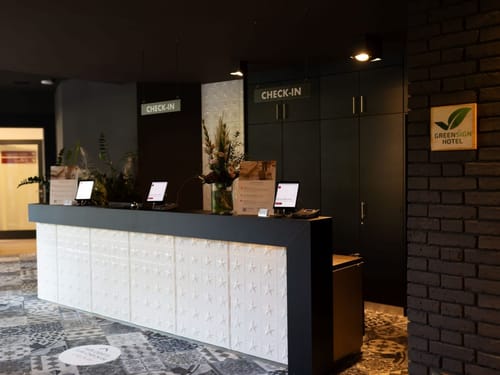 Empfangsbereich eines modernen Hotels mit Check-in-Schalter und Greensign-Zertifizierung.
