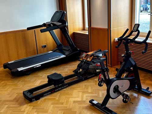 Fitnessgeräte im Raum mit Laufband, Rudergerät und Heimtrainer.