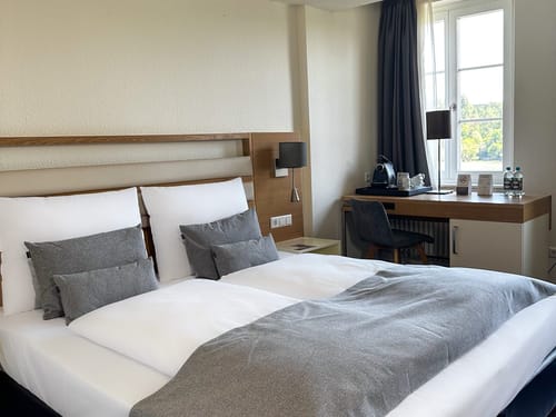 Hotelzimmer mit Doppelbett und Schreibtisch am Fenster
