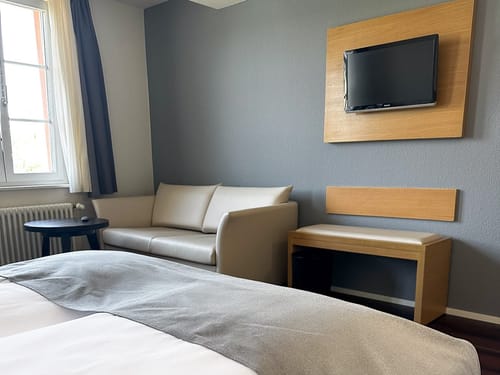 Hotelzimmer mit Couch und Flachbildfernseher an der Wand