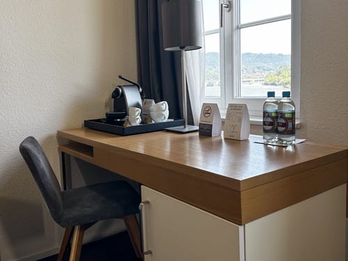 Schreibtisch im Hotelzimmer mit Kaffeemaschine und Wasserflaschen
