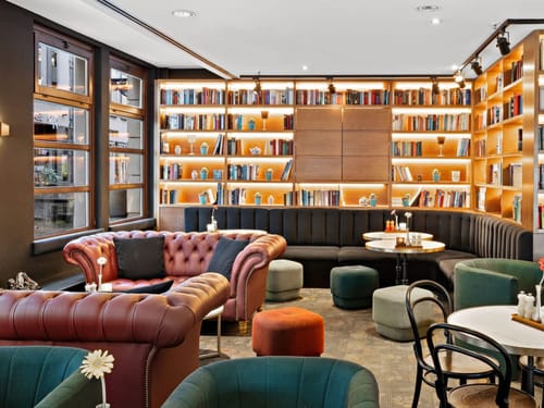 große Bücherwand mit verschiedenen Sitzmöglichkeiten in der Bibliothek