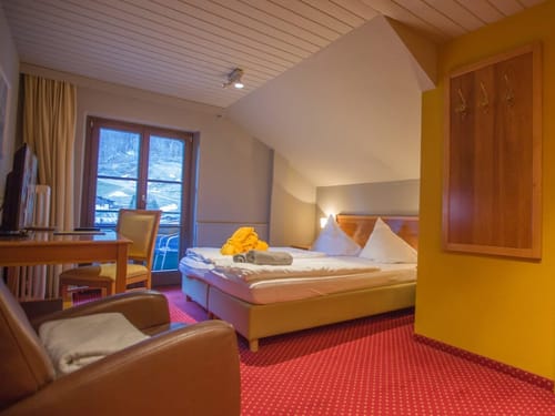 geräumiges Doppelzimmer mit Doppelbett, Tisch, Stuhl, TV und Balkon