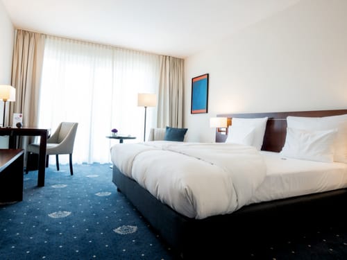 Modernes Hotelzimmer mit gemütlichem Doppelbett, stilvoller Einrichtung und großem Fenster.