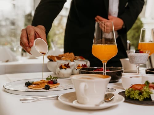 Elegantes Frühstück mit Orangensaft, Pfannkuchen und Kaffee
