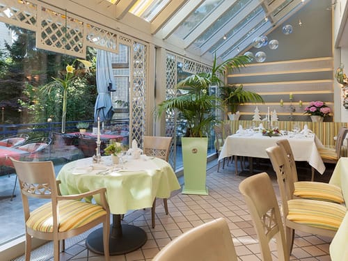 Helles und elegantes Restaurantambiente mit Glasfront und stilvoll gedeckten Tischen.