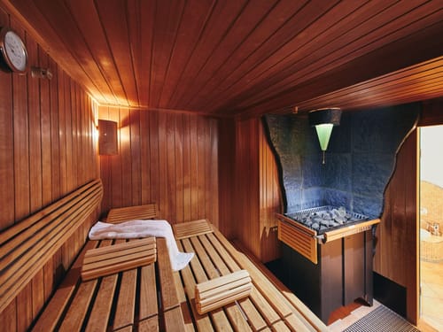 Gemütlicher Innenraum einer traditionellen Sauna mit Holzbänken und Saunaofen