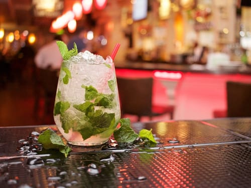 Erfrischender Mojito-Cocktail mit Minzblättern auf einer Bar in gemütlicher Atmosphäre.