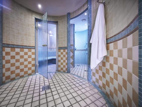 Moderner Duschbereich in einem Spa mit gefliesten Wänden und Glastür