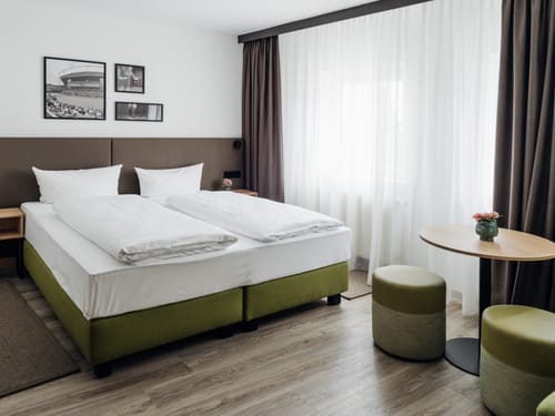 Standard Doppelzimmer mit Boxspringbett, Nachttischen, Hocker und Tisch